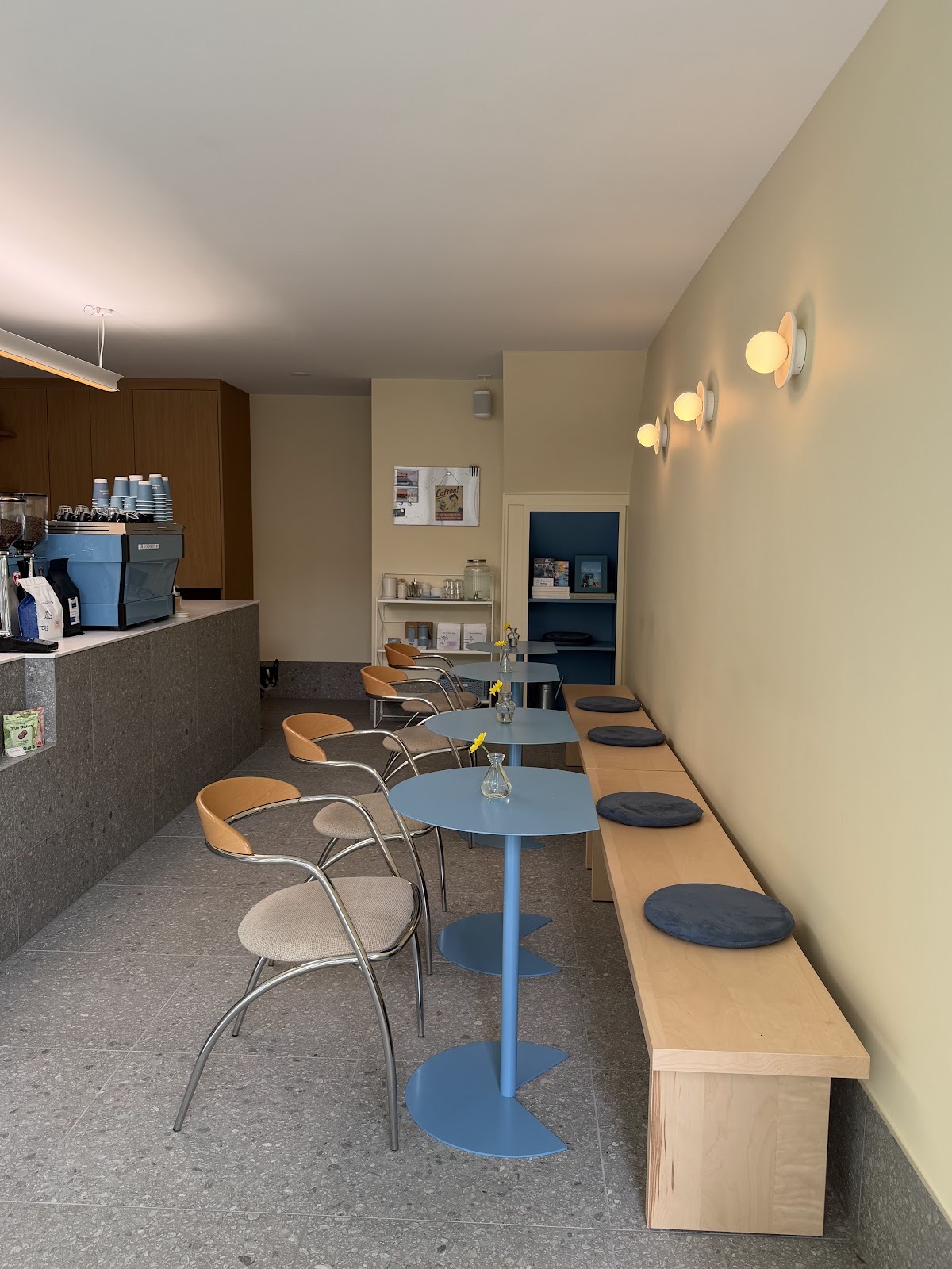 La salle du café: tables bleu ciel, banc de bouleau, murs beurre frais